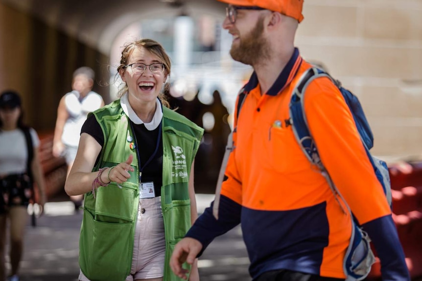 young woman laughing and trying to get attention of man in high vis walking by