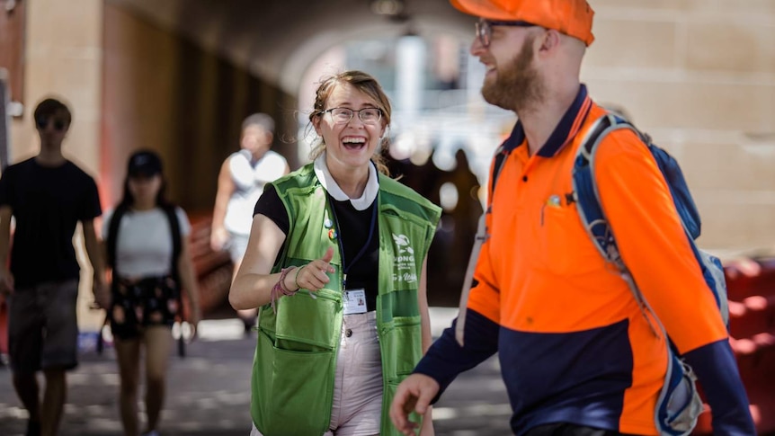 young woman laughing and trying to get attention of man in high vis walking by