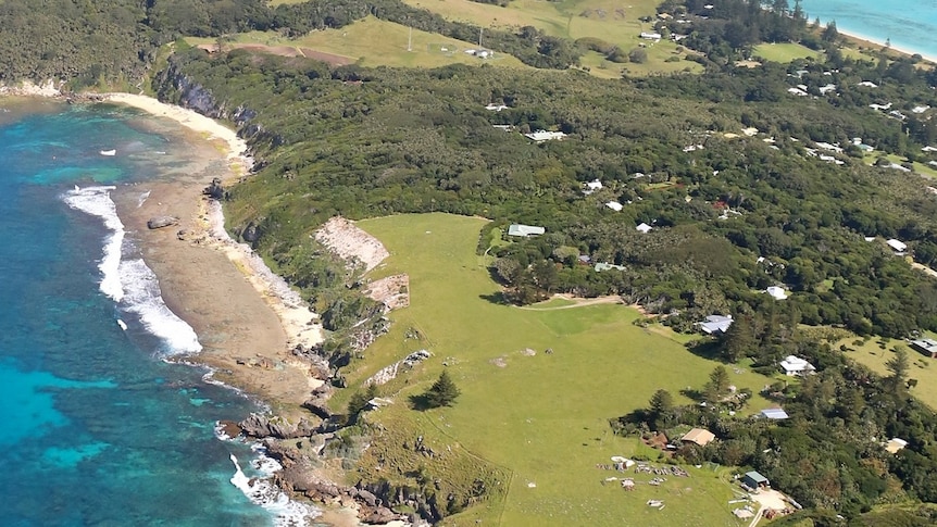 An aerial view of Lord Howe Island cliffs, beach and a few scattered houses