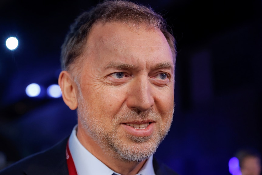 Head shot of a caucasian man in a suit, attending a forum, with white facial stubble