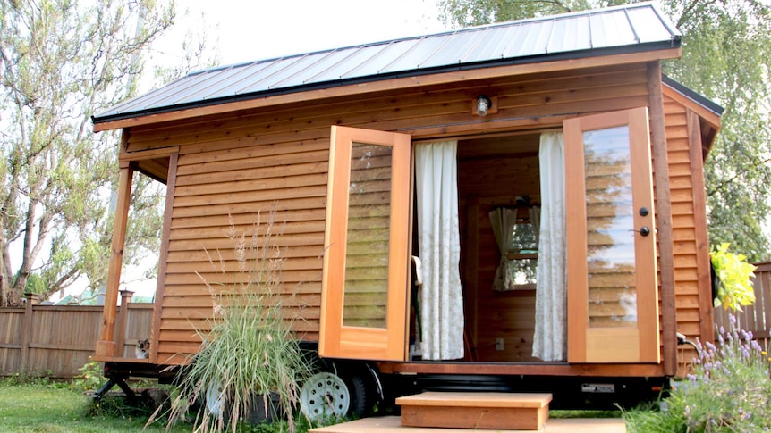 A tiny house with wheels in a backyard.