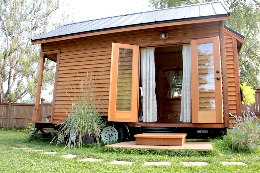 A tiny house with wheels in a backyard.