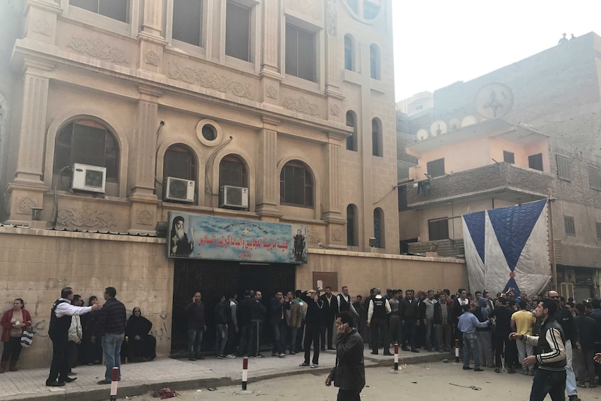 People are seen outside the Mar Mina Church after an attack,