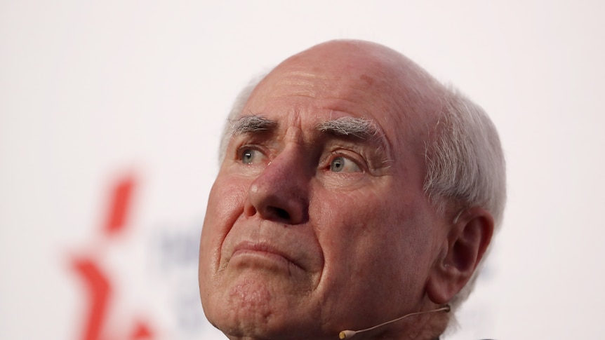John Howard sits looking into the distance