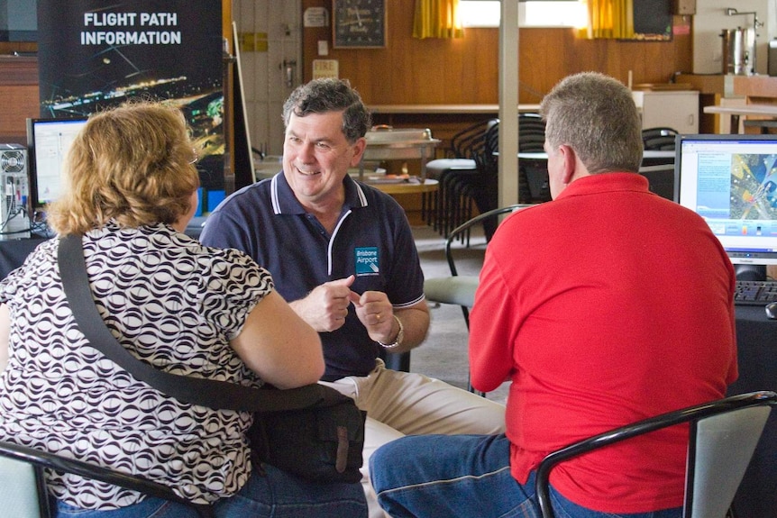 Paul Coughlan sits and discusses new flight paths with two people.