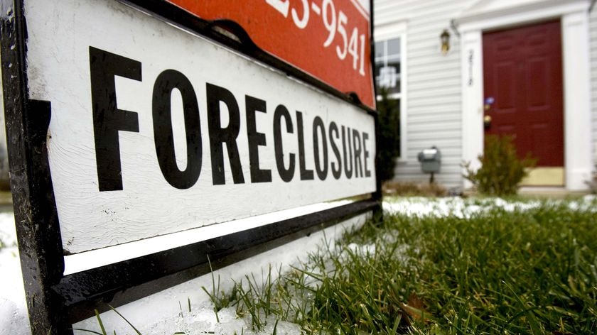 A foreclosure sign sits in front of a townhouse