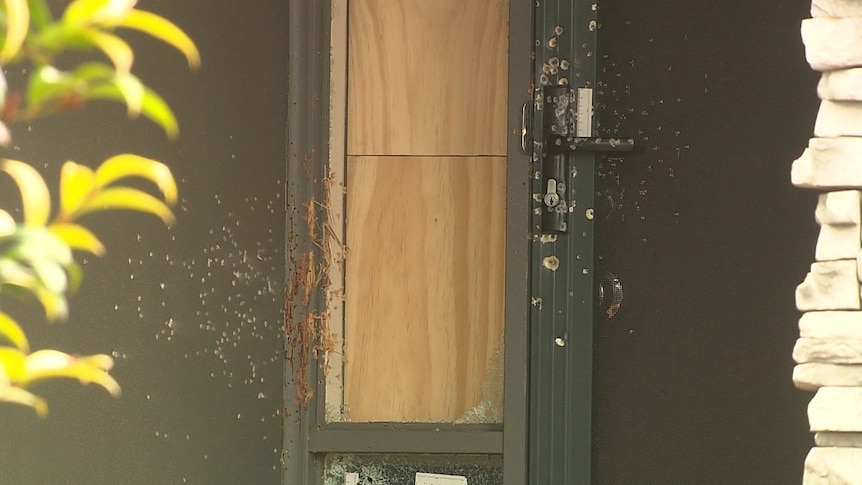 gun shot markings on a screen door and a side window boarded up