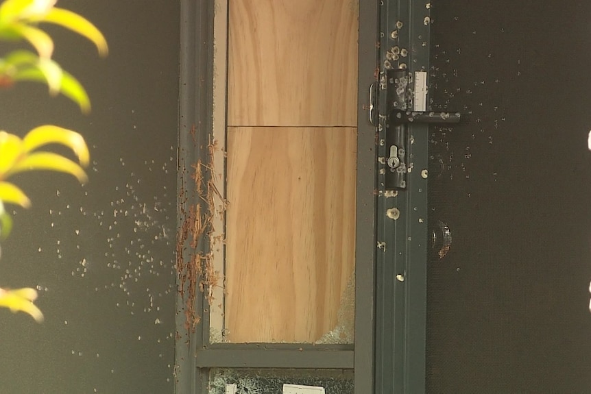 gun shot markings on a screen door and a side window boarded up
