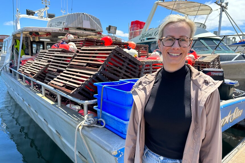Emily Rowe stands on a marina next to a boat filled with the new pot. 