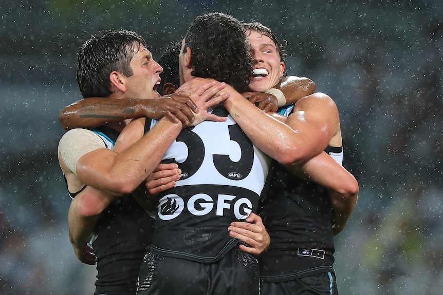 Port Adelaide players Zac Butters, Darcy Byrne-Jones and Zane Duursma hug