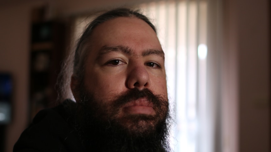 A man with long hair and a long beard looking at the camera 