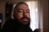 A man with long hair and a long beard looking at the camera 