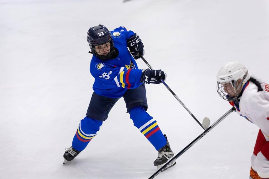A female ice hockey player for the Philippines women's team is swinging her stick during a game.