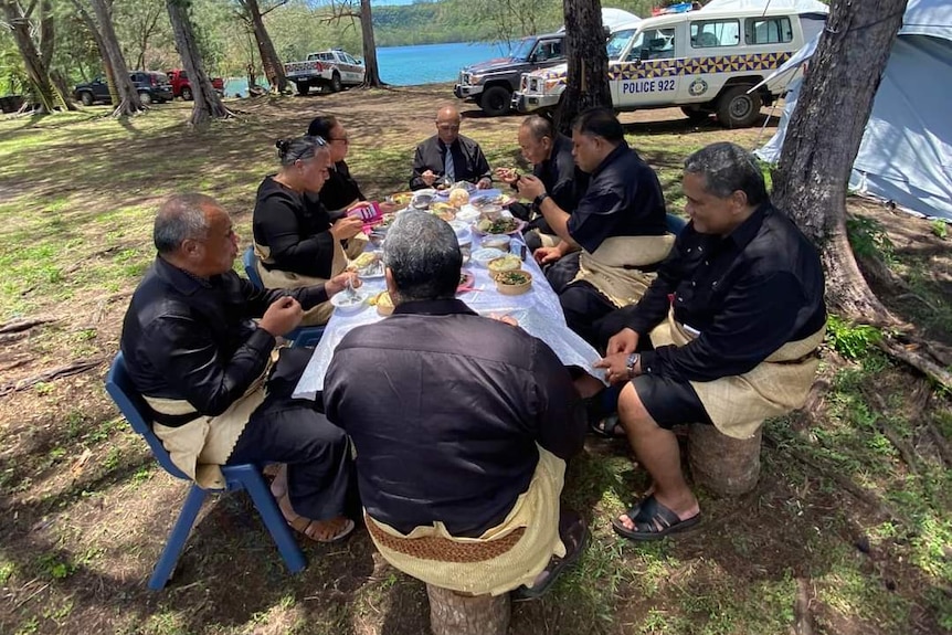 Tonga's prime minister Siaosi Sovaleni and ministers wearing black and having lunch at a table.