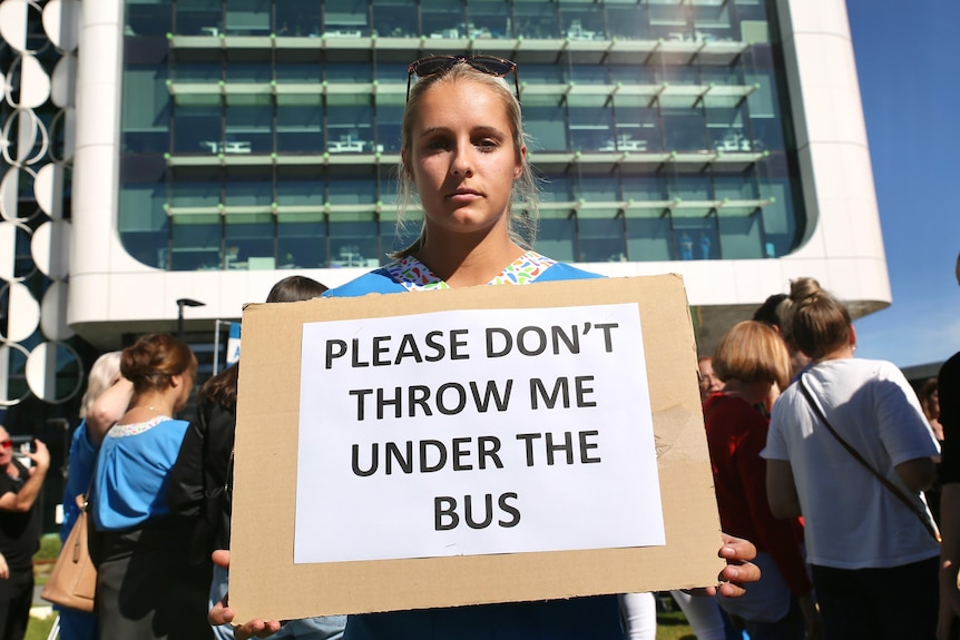 Shannon wears her nursing attire, holding a sign at a rally outside the Perth Children's Hospital.