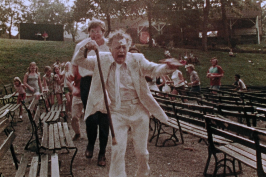 Film still of Lincoln Maazel running and screaming, holding his cane, in The Amusement Park