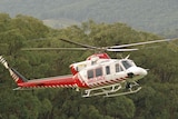 A white-and-red air ambulance helicopter in the sky.
