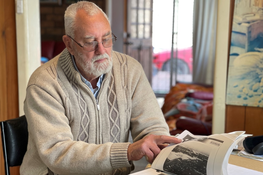 A man looks at documents on a table in his home.