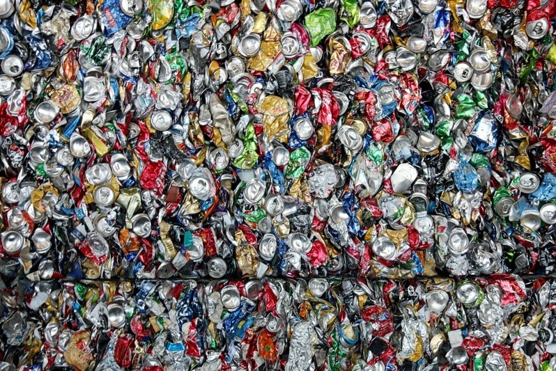 Hundreds of soft drink cans crushed and packed into a cube at a recycling centre.