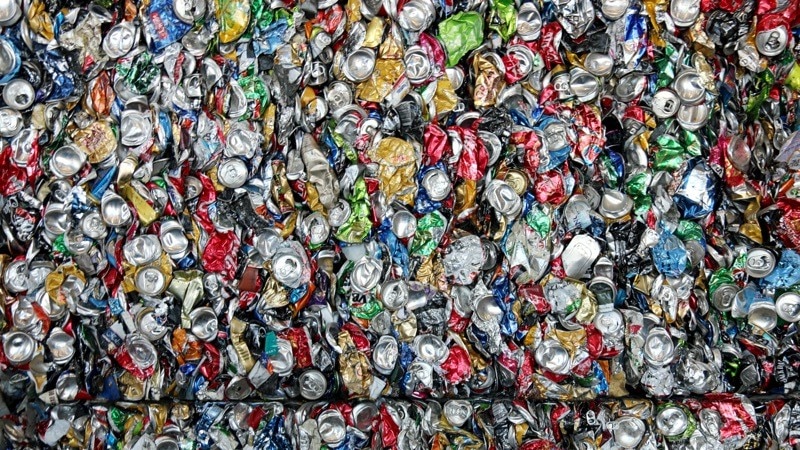 Hundreds of soft drink cans crushed and packed into a cube at a recycling centre.