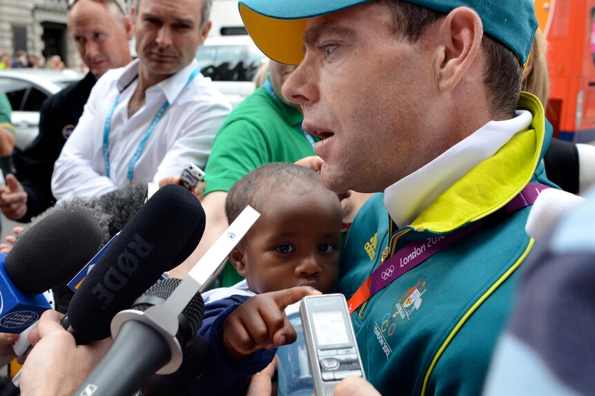 Cadel Evans holds his son as he speaks to the media following the road race.