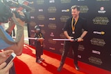A young Star Wars fan and an older one, both wielding toy lightsabers.