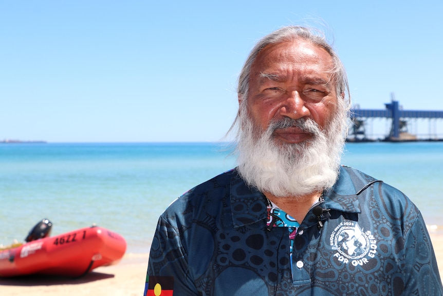 Headshot of an Indigenous man with a white beard on a beach