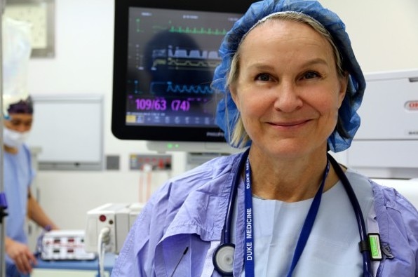 Uma mulher de vestido e rede no cabelo em um quarto de hospital. 