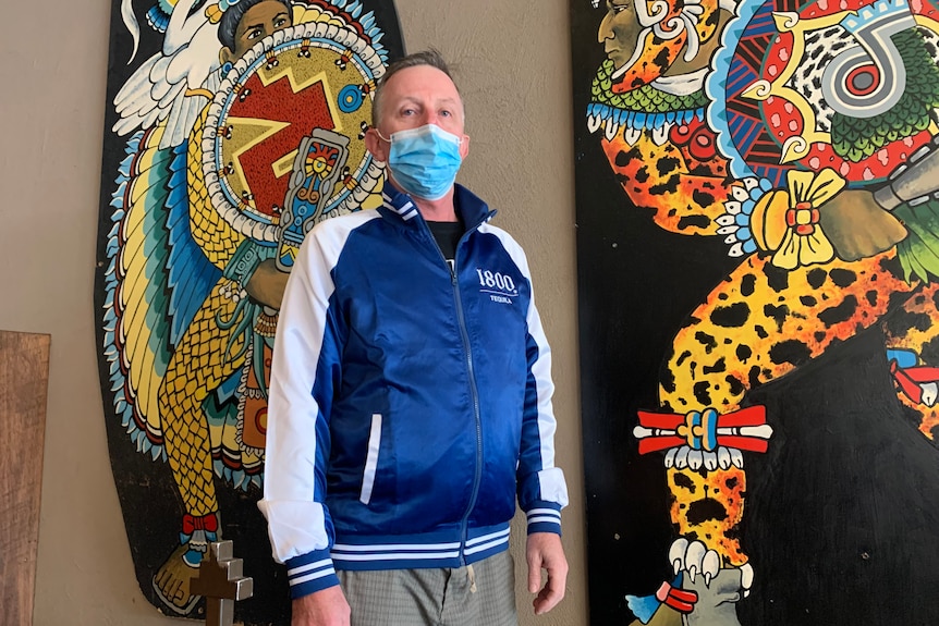 a man stands with a mask on outside a mexican restaurant