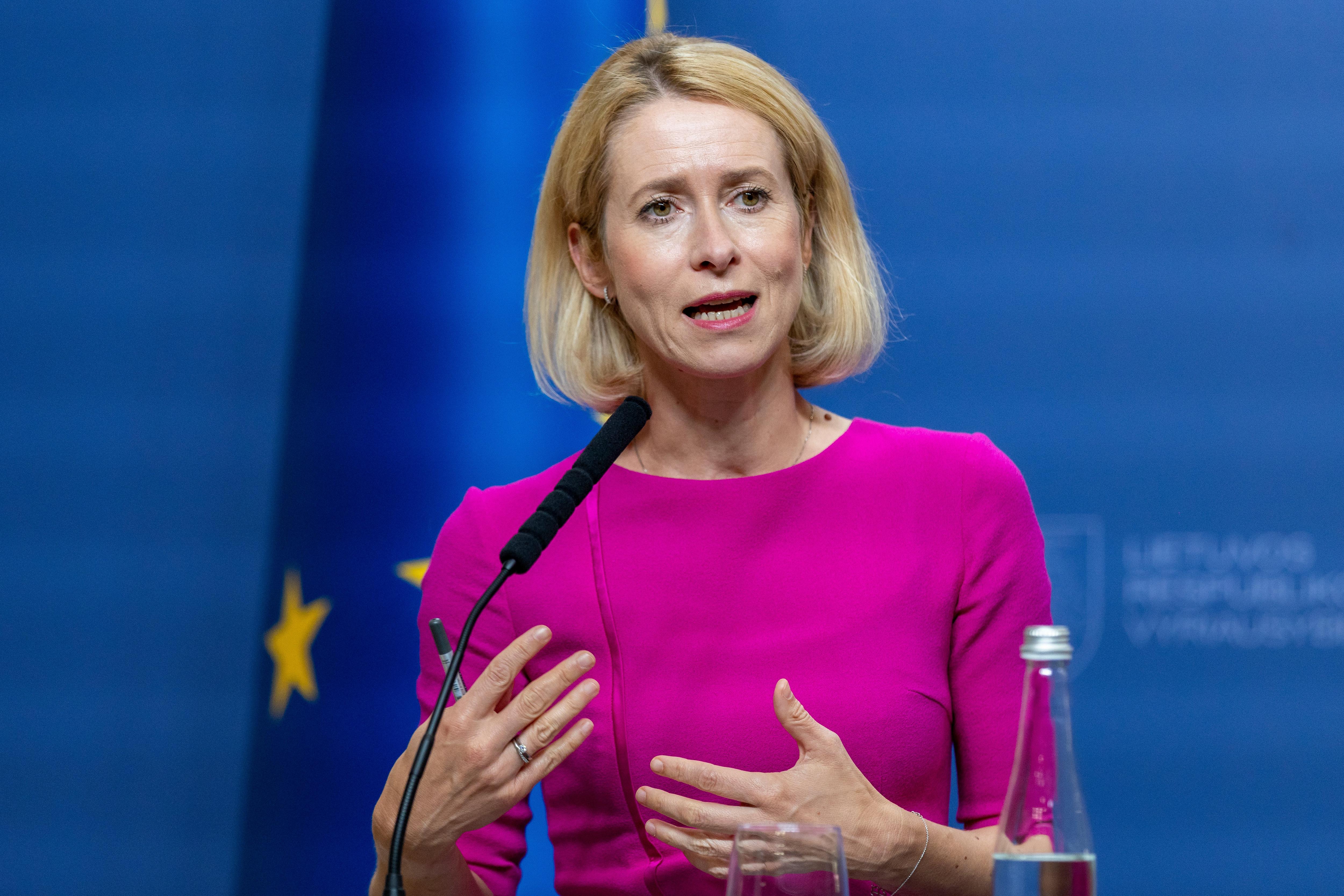 Kaja Kallas wearing a red dress, speaking into a microphone.