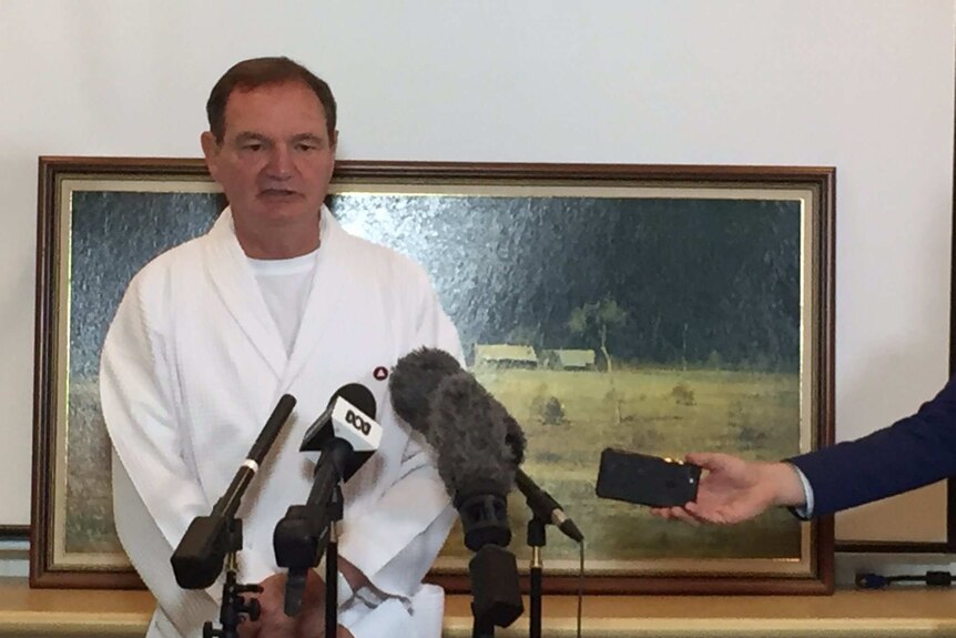 Ipswich Mayor Paul Pisasale in a white hospital gown in front of some microphones