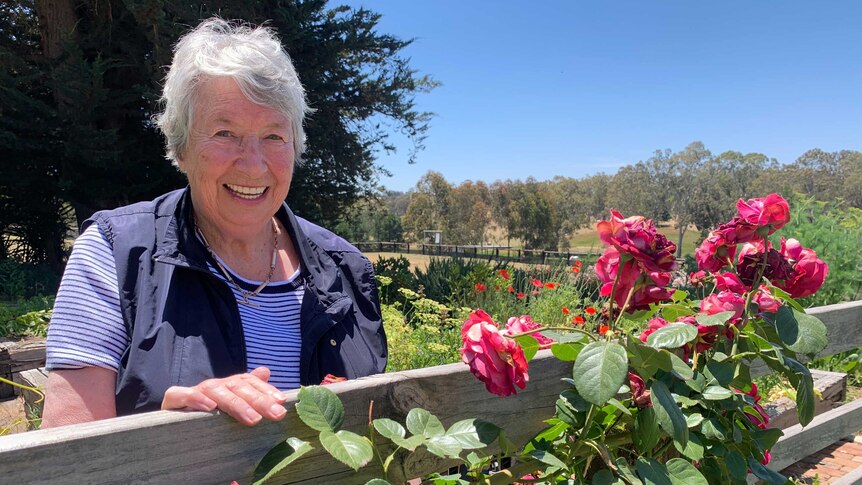 Judith Leeson AM standing in front of roses at home in the Adelaide Hills.