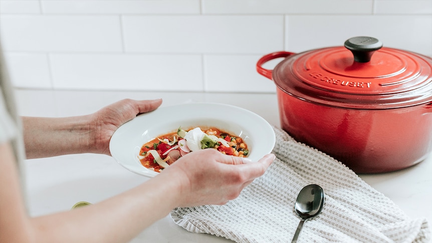 Woman holding a bowl of what looks like chicken and vegetable soup