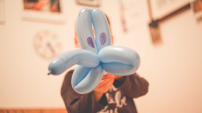 A child playing with a balloon shaped like a dog.