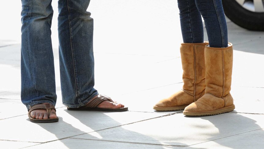 A woman in ugg boots next to a man in sandals visible from the knee down.