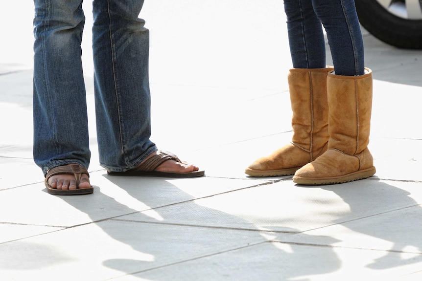A woman in ugg boots next to a man in sandals visible from the knee down.