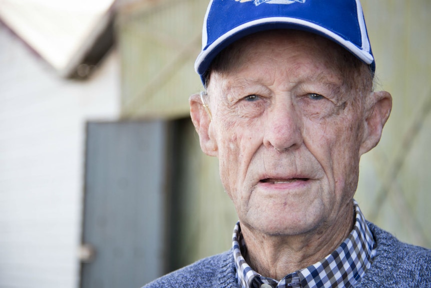 An elderly man wearing a blue cap, looking at the camera.