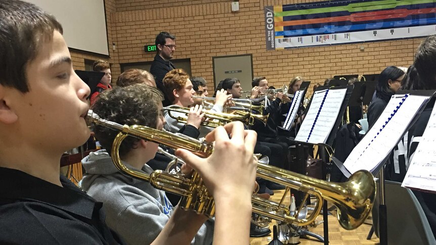 Young students play trumpets in an orchestra.