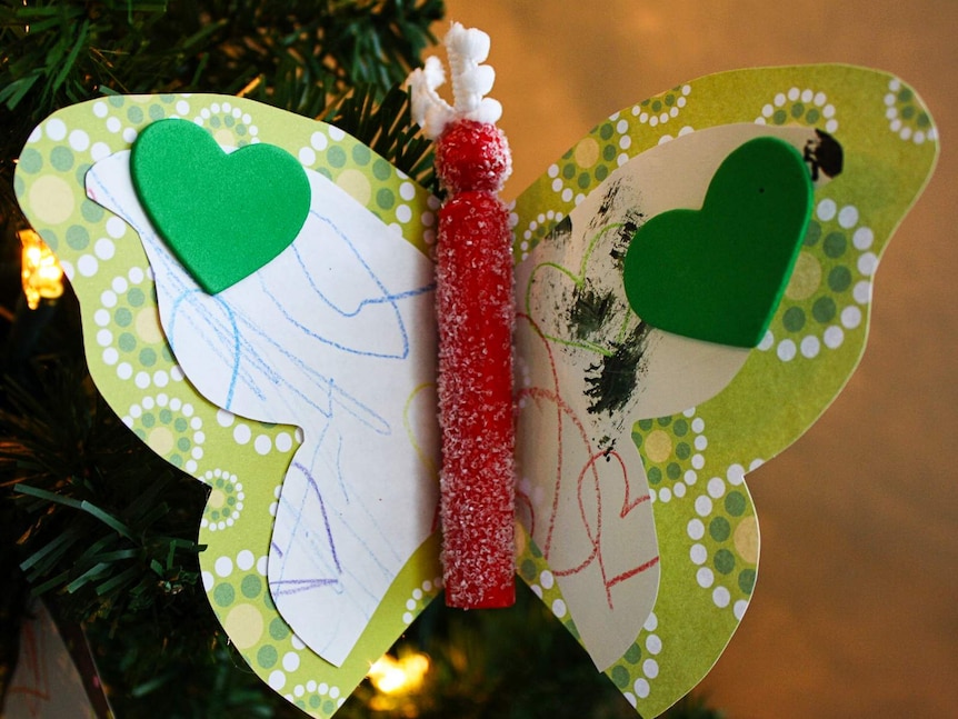 An Christmas ornament in the shape of a butterfly made from a child's artwork.