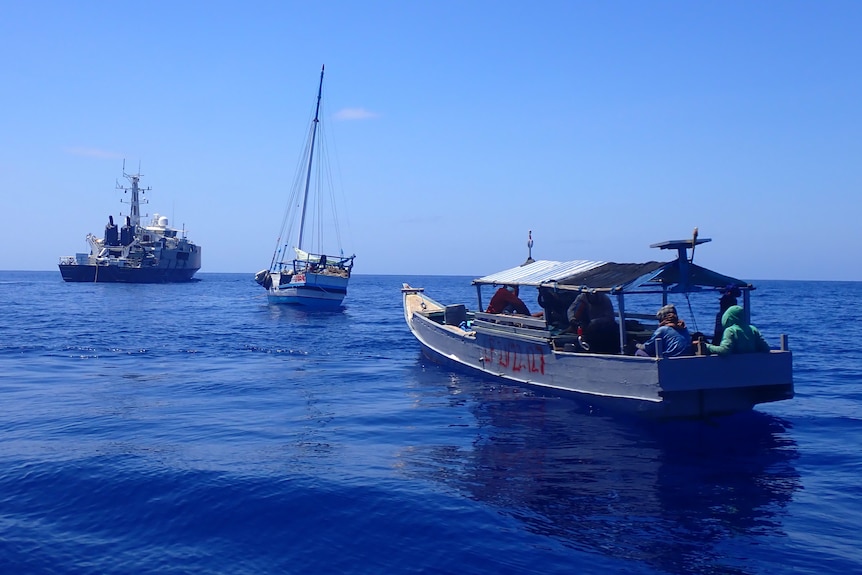 Multiple boats in ocean including Border Force patrol boat and small illegal fishing vessel