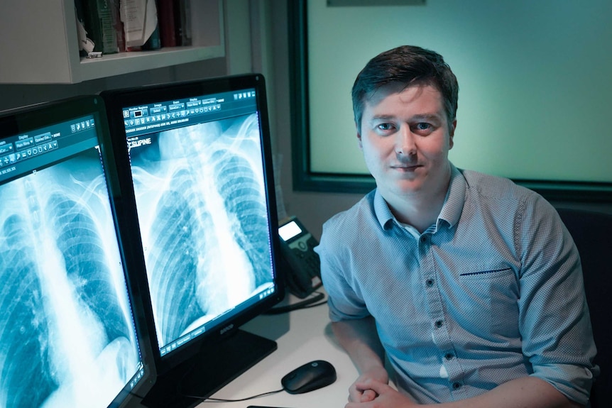 Dr Andrew Dixon sits in front of a computer showing a scan of a patient's lungs.