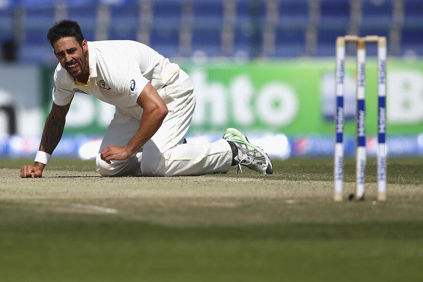 Mitchell Johnson lays on the pitch in Abu Dhabi
