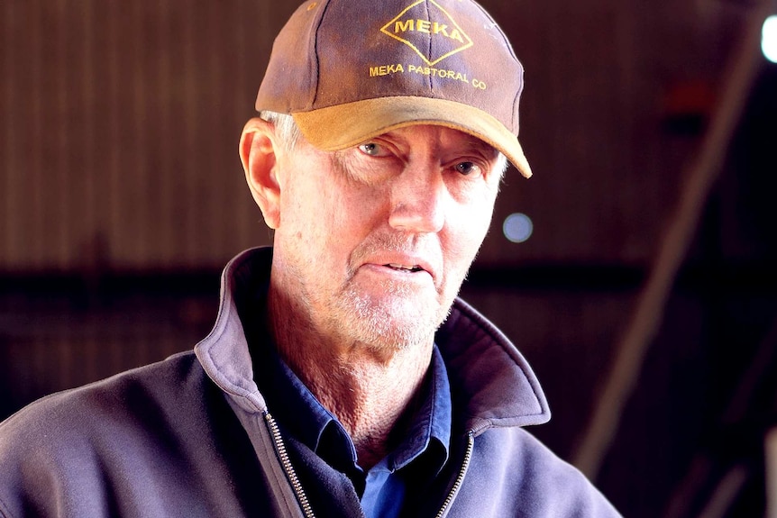 A man wearing a cap looks at the camera