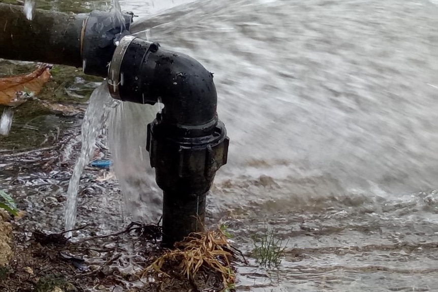 Water is gushing out of a pipe connected to a rainwater tank on Manus Island