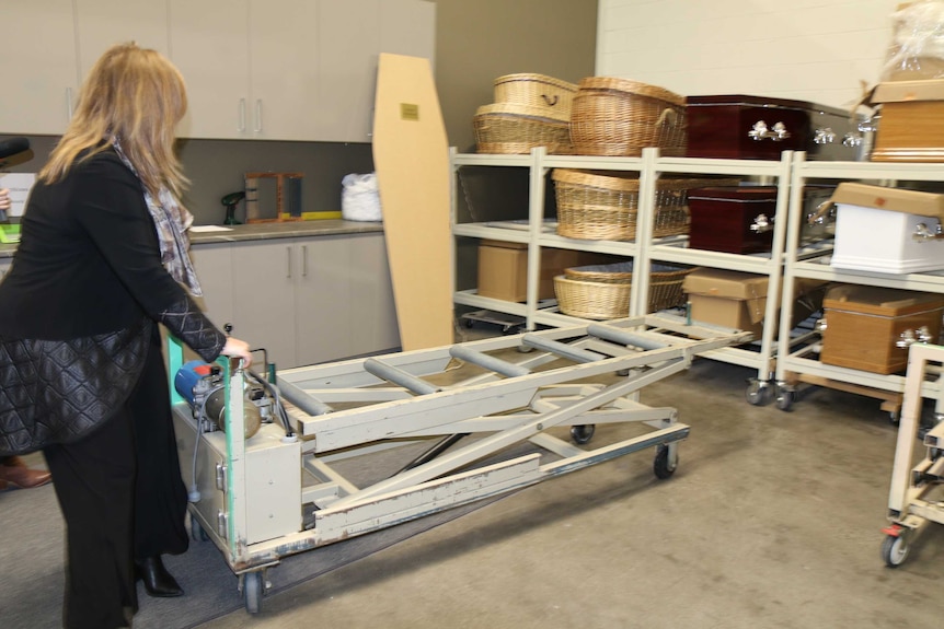 A woman moves coffins about at the funeral home.