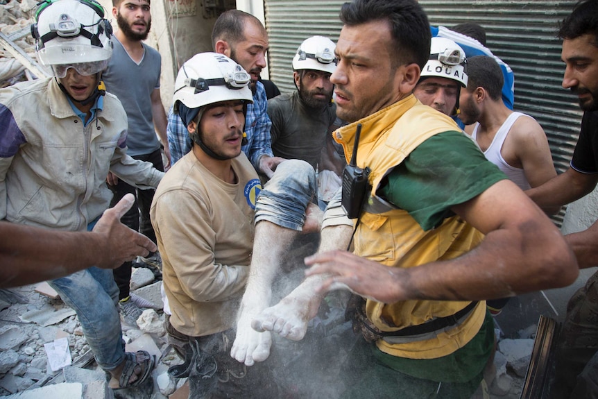 Syrian civil defence volunteers, known as the White Helmets, carry a body in Aleppo.