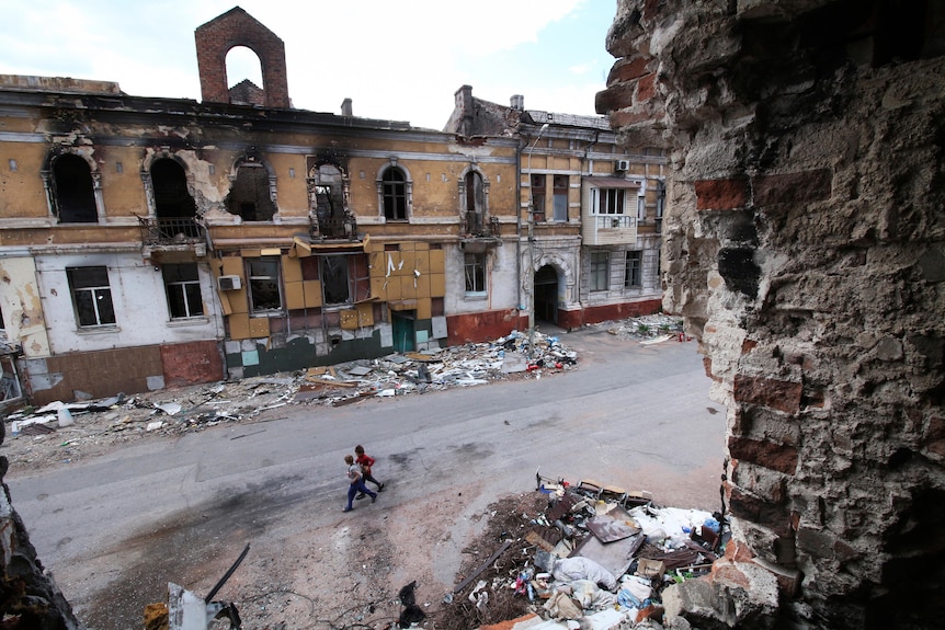 Children walk amid destroyed buildings in Mariupol.