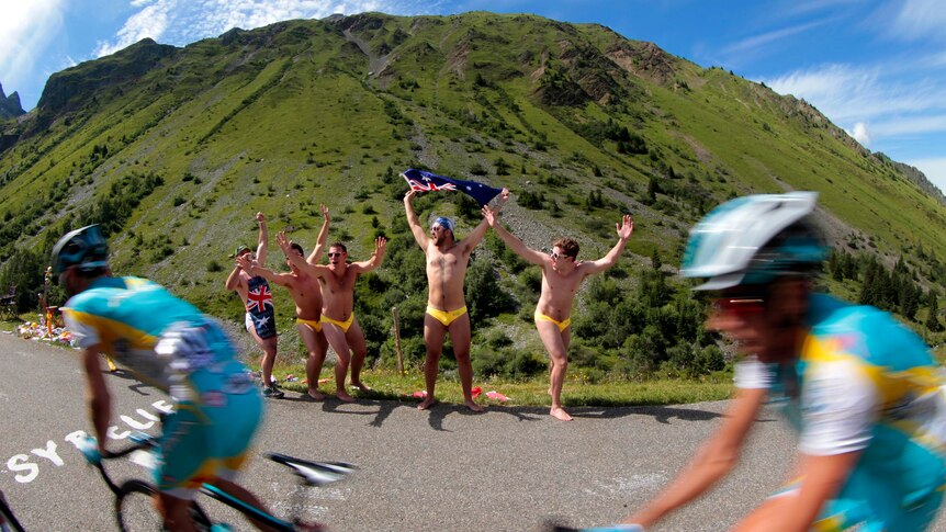 Fans wave the Australian flag as the pack rides past in the 2012 Tour de France.