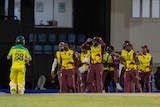An Australian batsman trudges off as the West Indies cricketers celebrate victory on the oval.