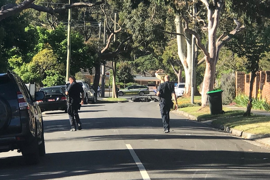 Police officers at the scene of a hit and run at Mitcham, with a motorcycle on the road.